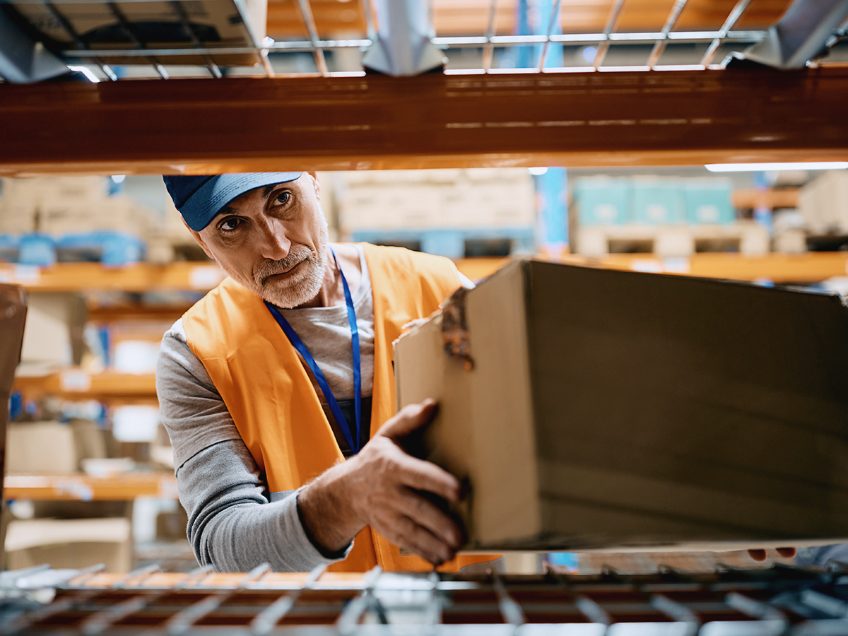 A warehouse employee observing proper warehouse slotting as he organizes packages